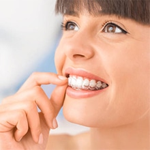 Woman flossing teeth with bright smile against blue background, dental care demonstration.