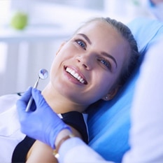 Woman smiling during dental examination in modern dental office setting.