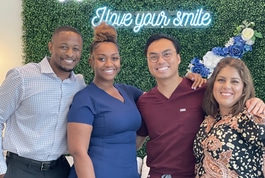 Four smiling dental professionals posing together in front of Prosper Smile Studio branded backdrop.