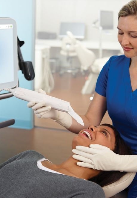 Dentist in blue scrubs examining patient's teeth in modern dental office with city skyline view.