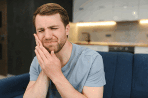 Man holding his cheek in pain, experiencing tooth discomfort in Prosper, TX.