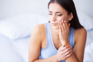 Woman experiencing tooth pain, holding her cheek in discomfort.