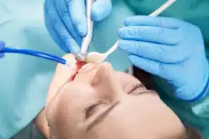 Dentist performing laser gum treatment on patient's swollen gums during dental procedure.