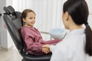 Young patient in dental chair smiling at dentist during checkup visit.